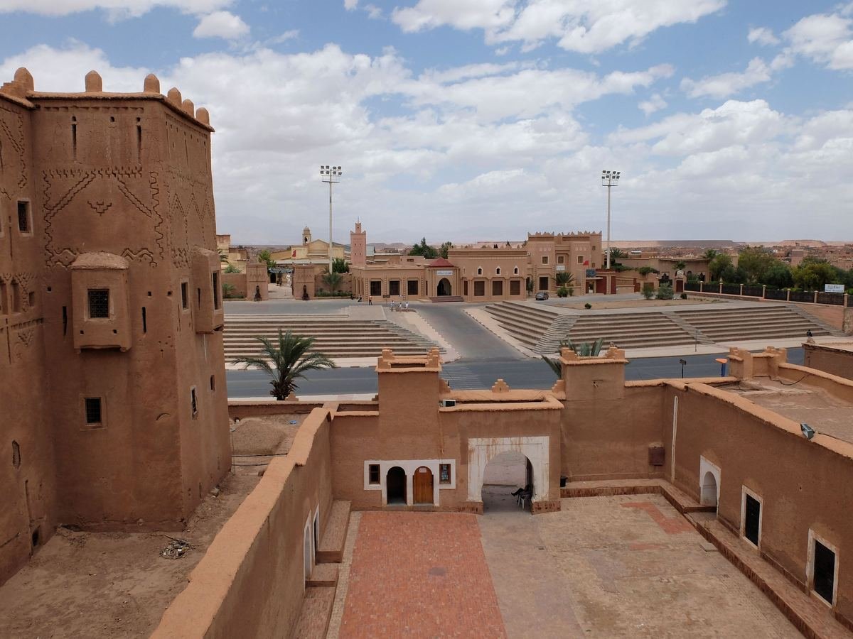 Entrance courtyard of Kasbah Taourirt with an earthen tower, looking across the road to the square opposite