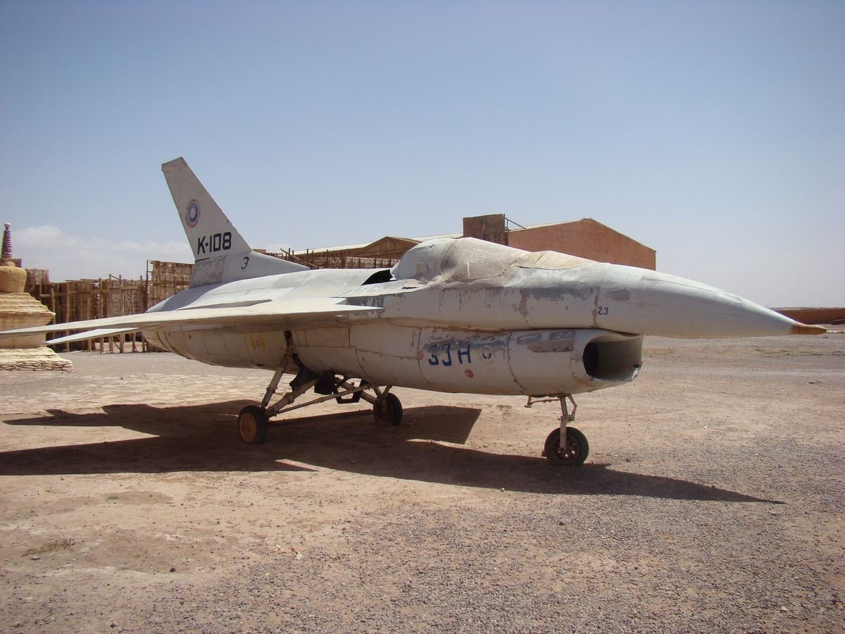 Avion de chasse blanc, accessoire du film Le Diamant du Nil, devant des décors aux studios Atlas