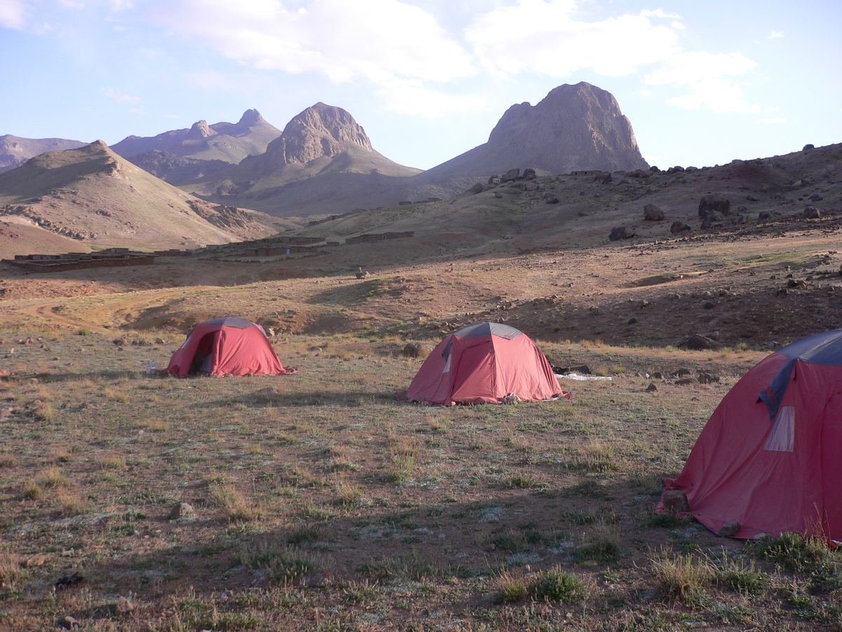 Tentes dans un pâturage d'altitude avec des pics volcaniques au fond, massif du Siroua