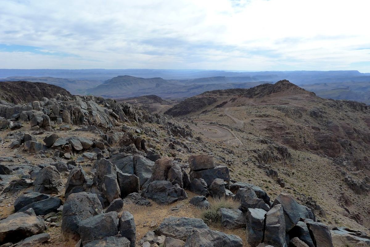 Blocs de roche volcanique sombre et vue dégagée depuis un col du Jbel Saghro