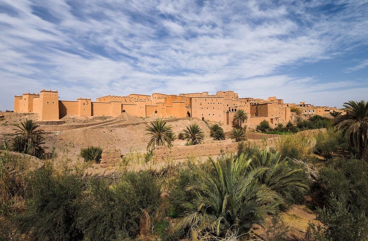 The Kasbah Taourirt in Ouarzazate seen above a palm grove under a wide sky