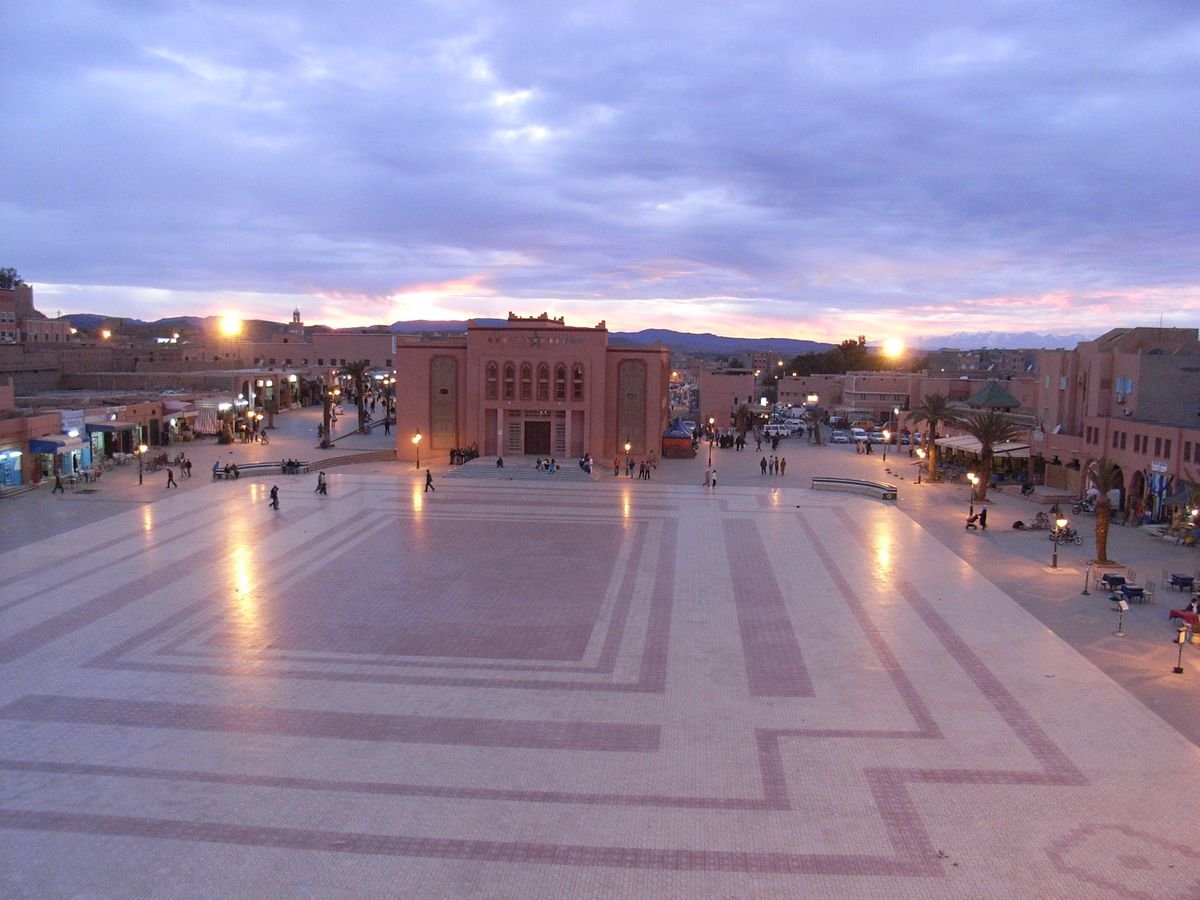 A street in central Ouarzazate with earthen-coloured buildings and palm trees