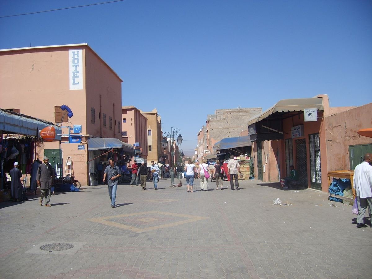 Rue piétonne commerçante du centre de Ouarzazate, avec boutiques et cafés sous un ciel bleu