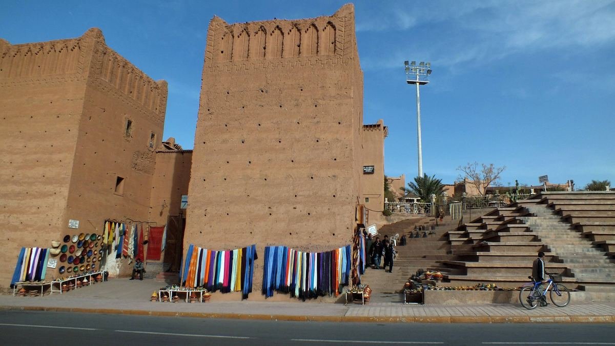 Tapis et couvertures exposés à la vente contre des murs en terre près de la kasbah de Taourirt à Ouarzazate