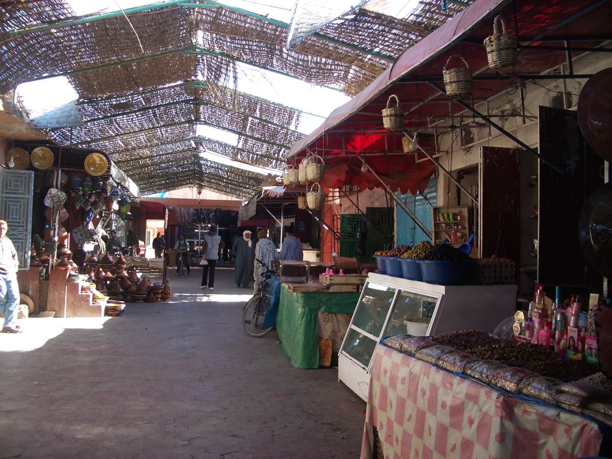 Une allée de souk couvert à Ouarzazate avec des étals de plats à tajine, de paniers, d'olives et de dattes