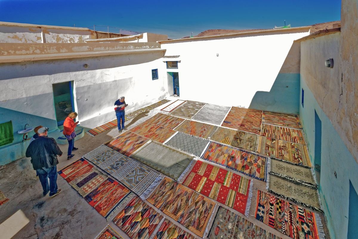 Hand-woven carpets laid out to dry in a whitewashed courtyard in Taznakht