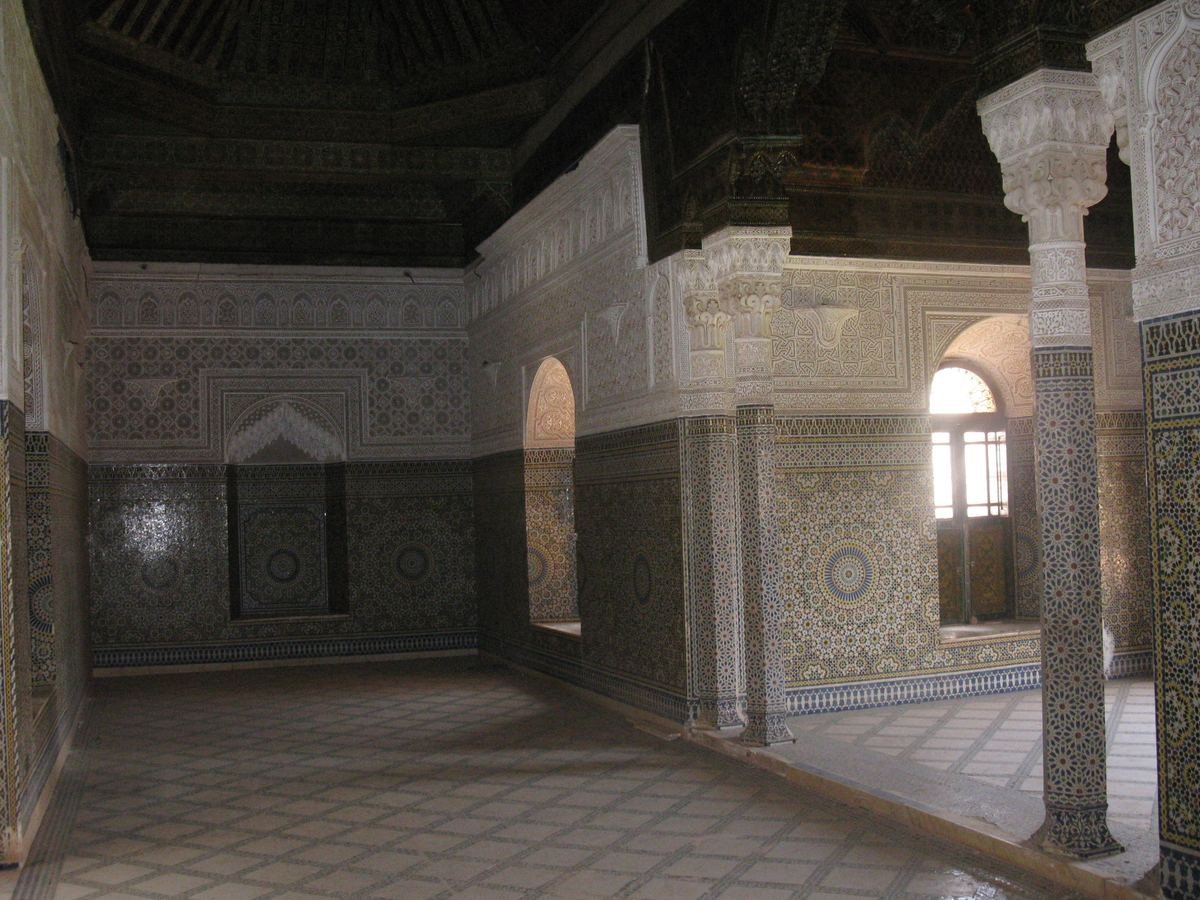 Reception hall of the Telouet kasbah with zellige tilework, carved plaster columns and a painted wooden ceiling